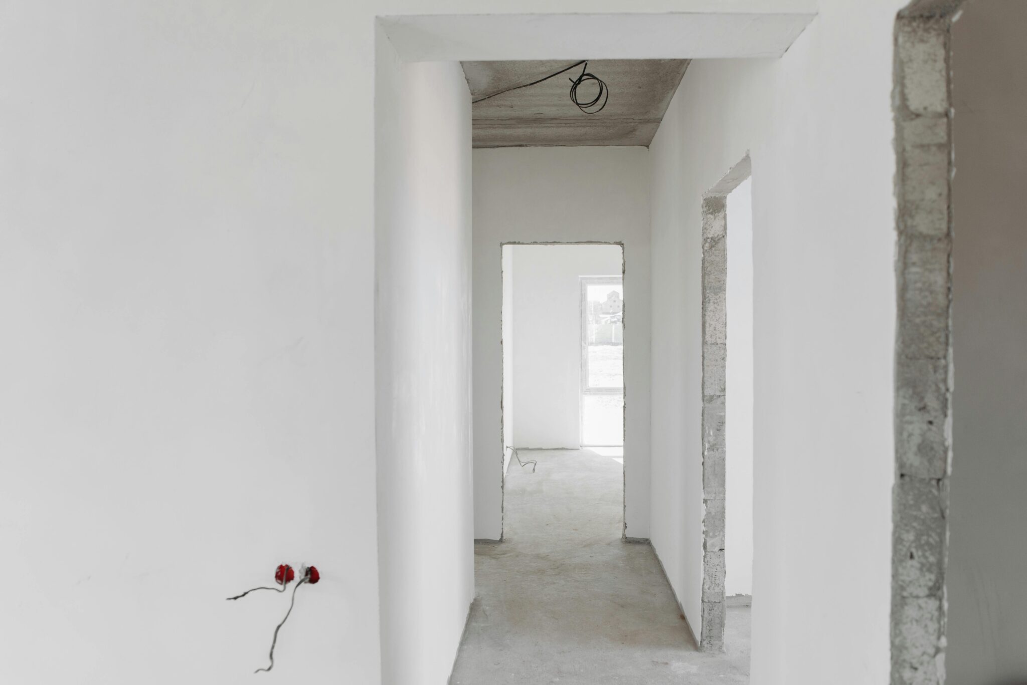 A minimalist view of an unfinished building interior with white walls and door frames.