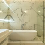 Elegant marble bathroom featuring a bathtub, sink, and glass shower enclosure.