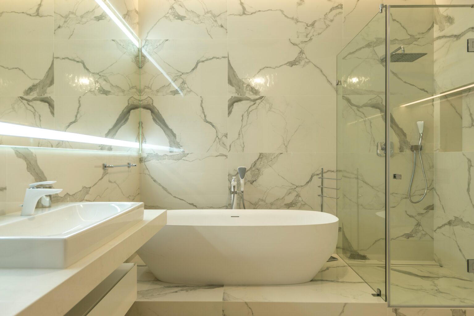 Elegant marble bathroom featuring a bathtub, sink, and glass shower enclosure.